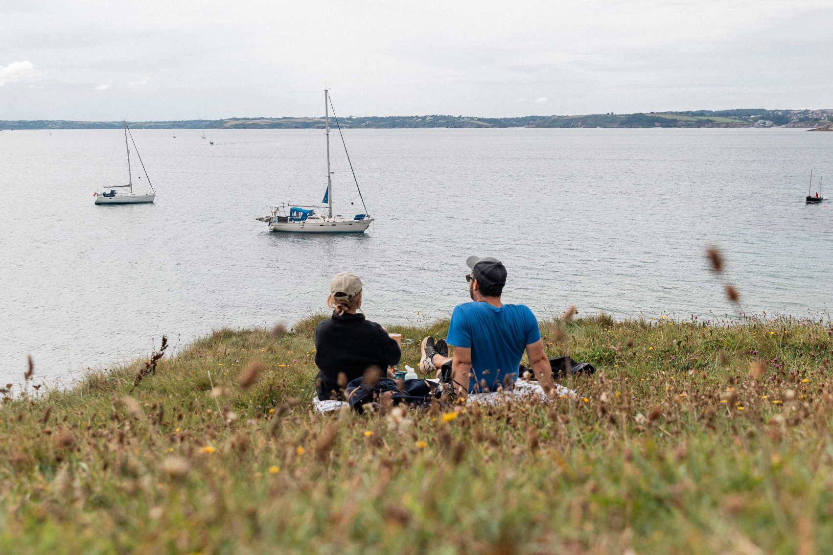A couple sitting on a clearing in the cliff tops overlooking the sea