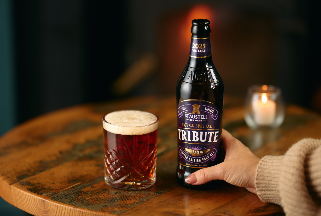 hand holding a bottle of Extra Special Tribute on a table next to a glass