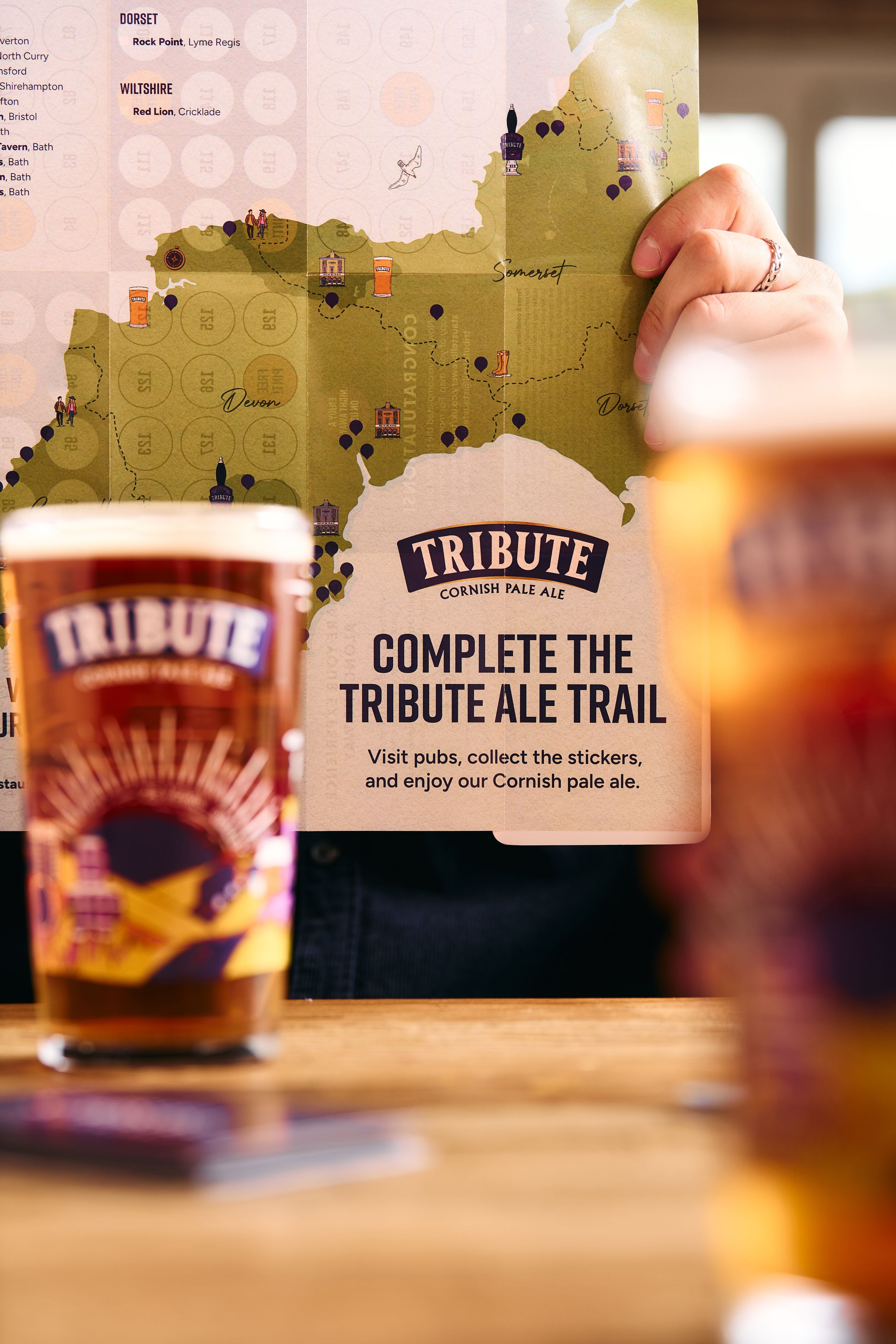 The Tribute Ale Trail Map 2026 being held up behind two pints of Tribute